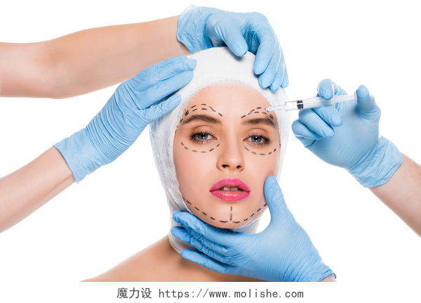 白色背景上在女士脸上做标记的整形医生穿着蓝色乳胶手套的整形外科医生的裁剪视图, 用注射器靠近妇女的脸, 在白色上查出痕迹 